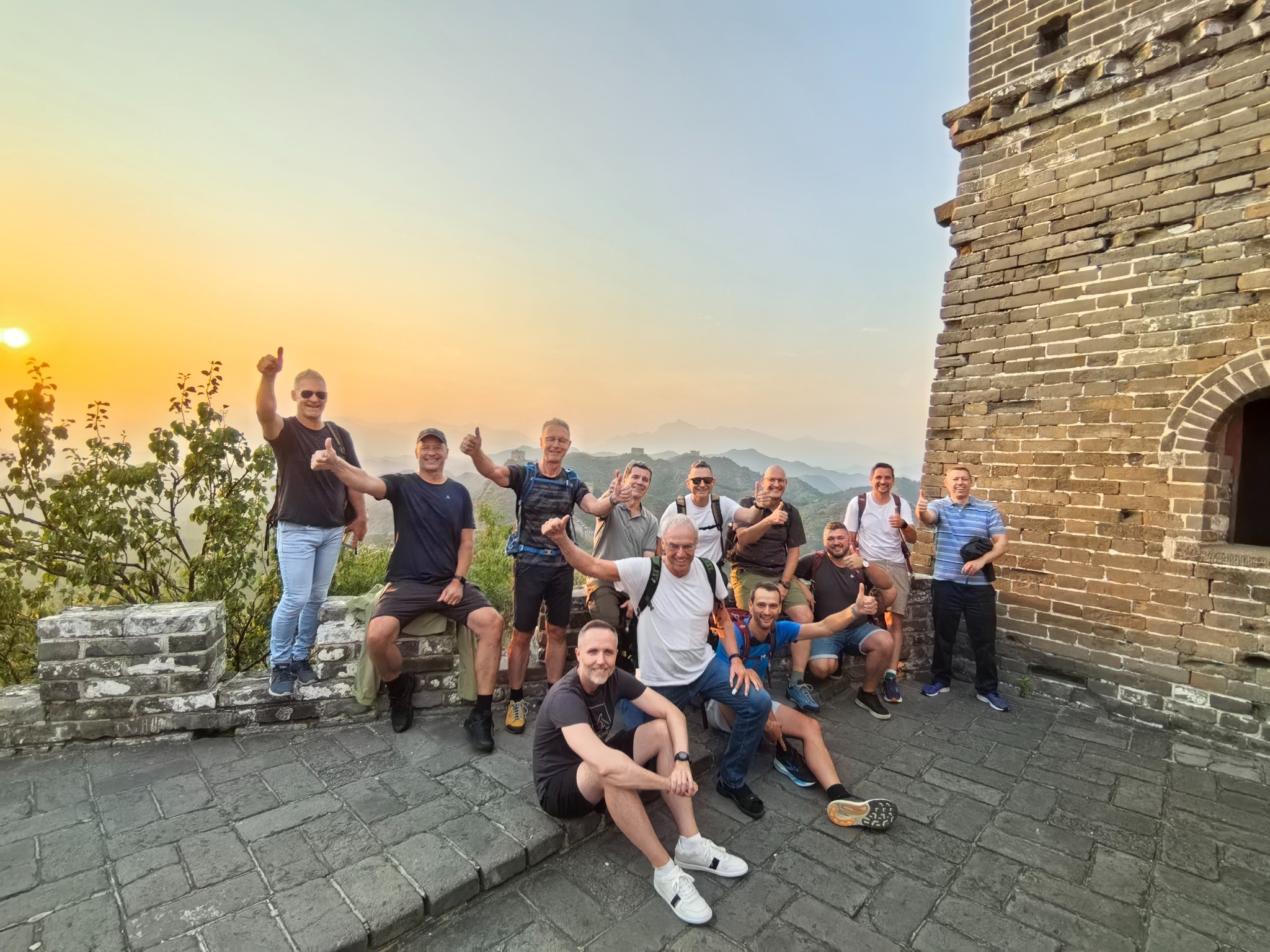 Great Wall hikers celebrating beside a watchtower at sunset